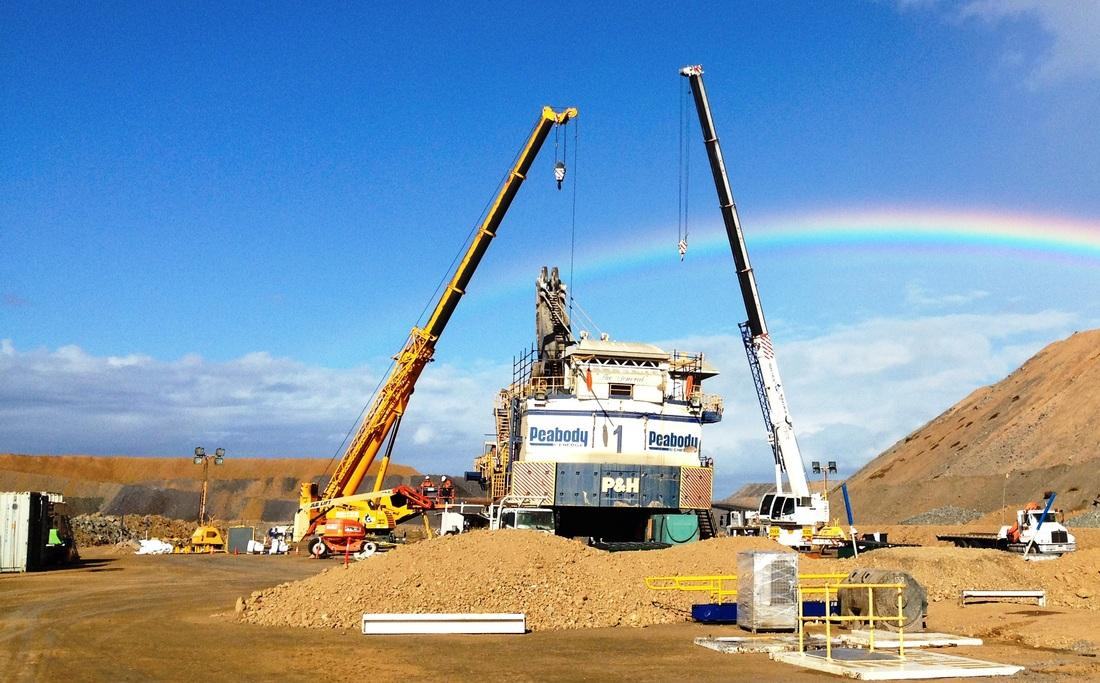 Two cranes rigged over a Peabody P&H face shovel during a field rebuild, rainbow behind