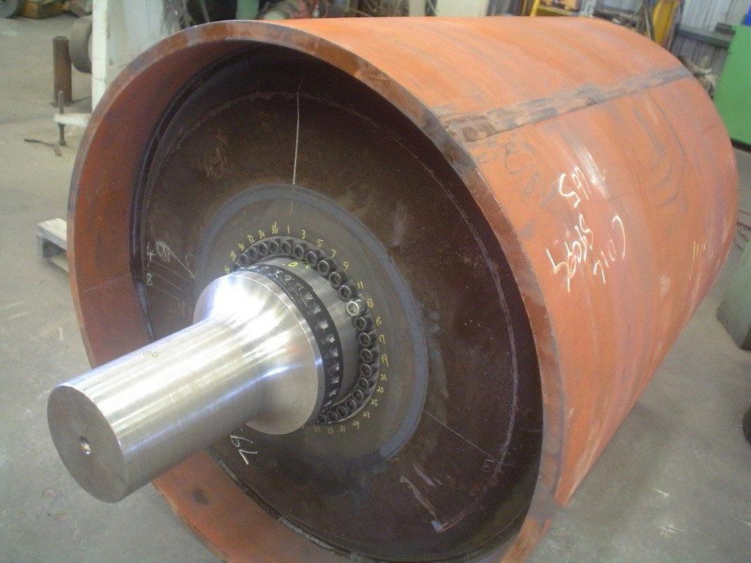 Large rebuilt conveyor pulley drum with a freshly machined steel shaft, red oxide primer finish