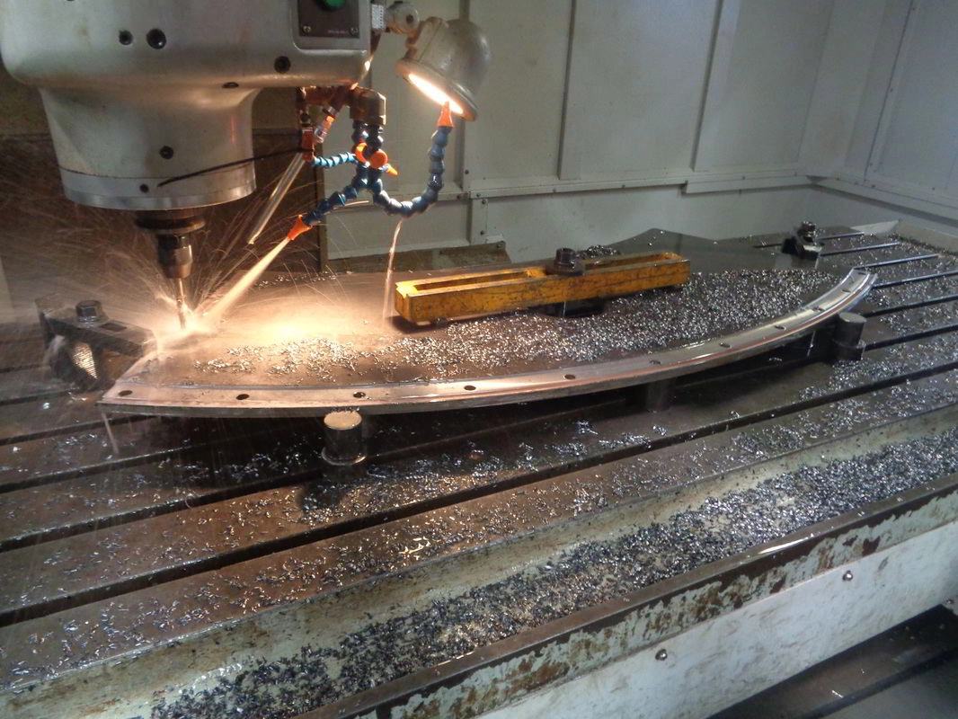 CNC floor borer machining a curved dragline bucket arch segment, sparks flying across the bed