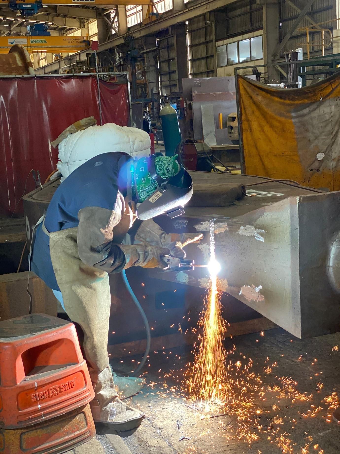 ABC Heavy Engineering boilermaker oxy-cutting a fabricated steel section in the Paget workshop, sparks streaming