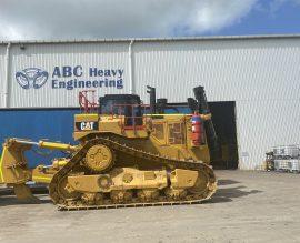 Caterpillar dozer parked on ABC Heavy Engineering hardstand with workshop buildings behind