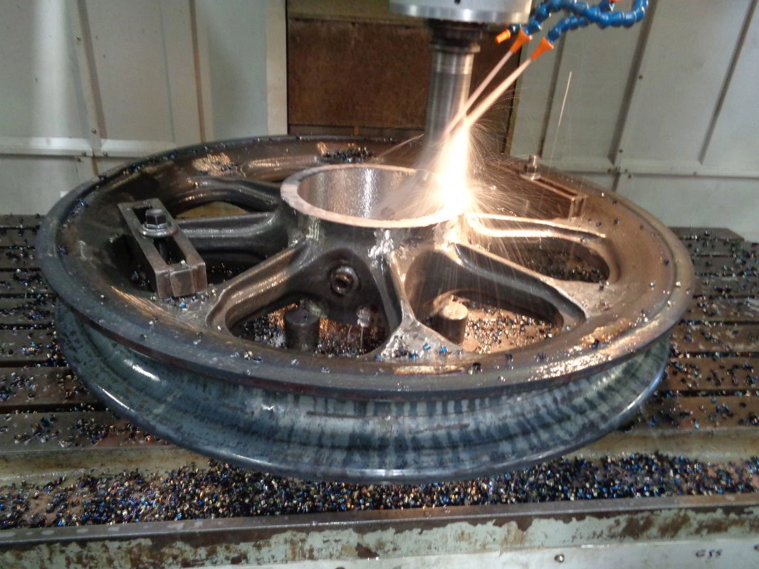 CNC milling machine cutting a large wheel component at ABC Heavy Engineering, sparks flying